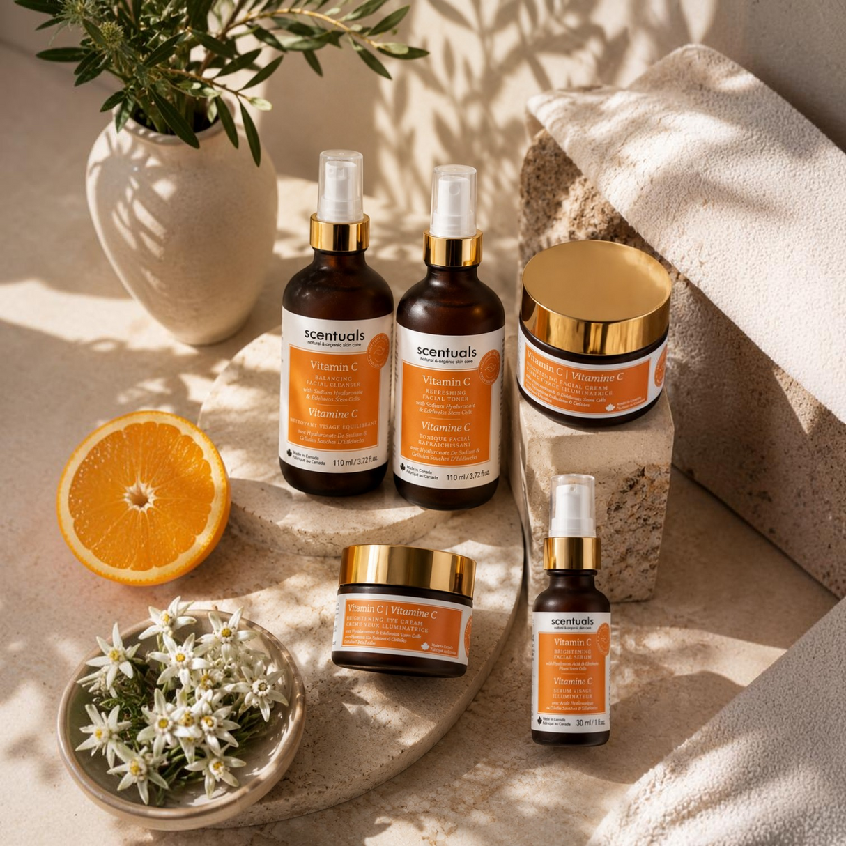 Scentuals Natural & Organic Skin Care Vitamin C serum duo and skincare collection on stone pedestals with orange slice