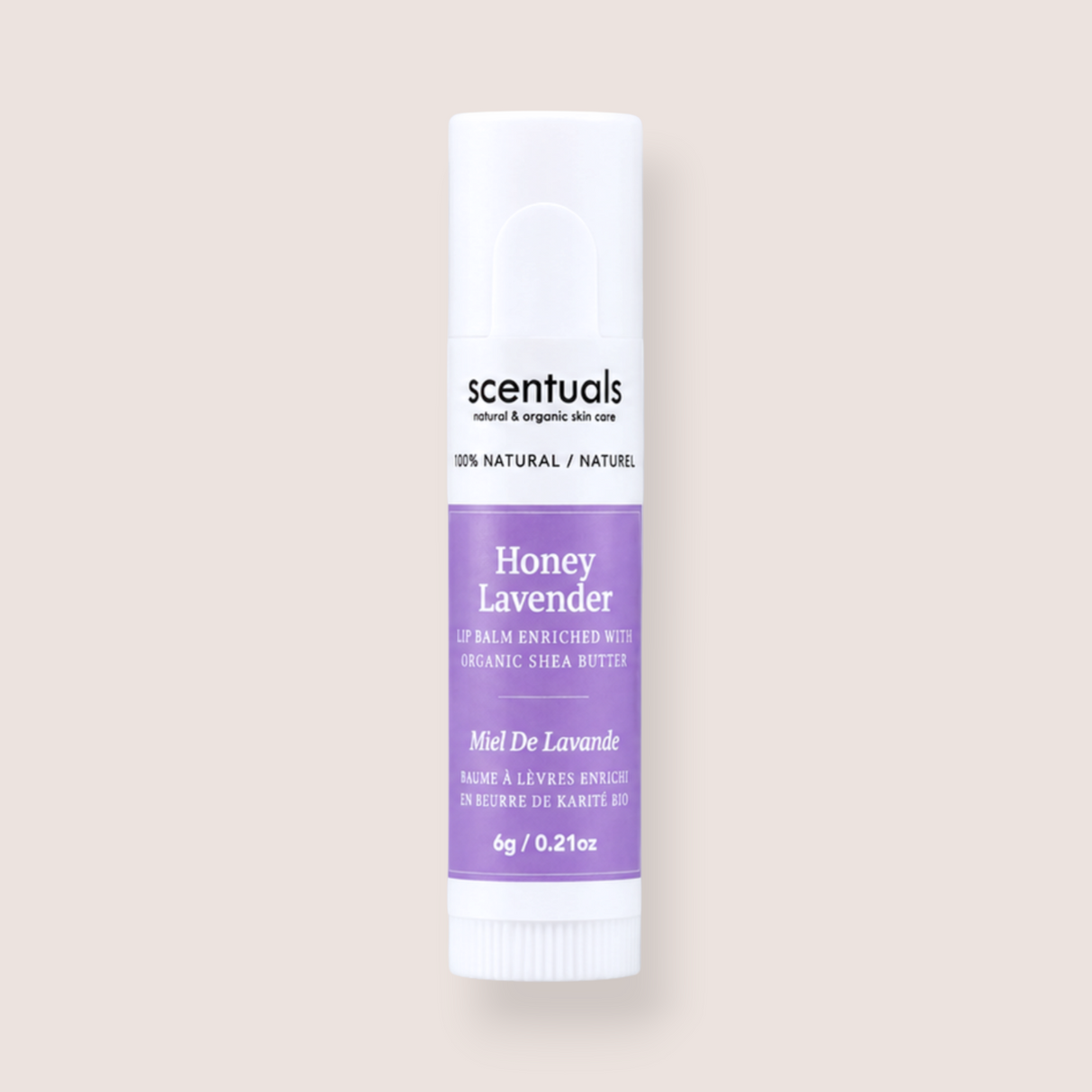 A single tube of Scentuals Honey Lavender lip balm centered on a solid, warm off-white background. The tube is white with a lavender purple label and black text.