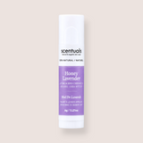 A single tube of Scentuals Honey Lavender lip balm centered on a solid, warm off-white background. The tube is white with a lavender purple label and black text.