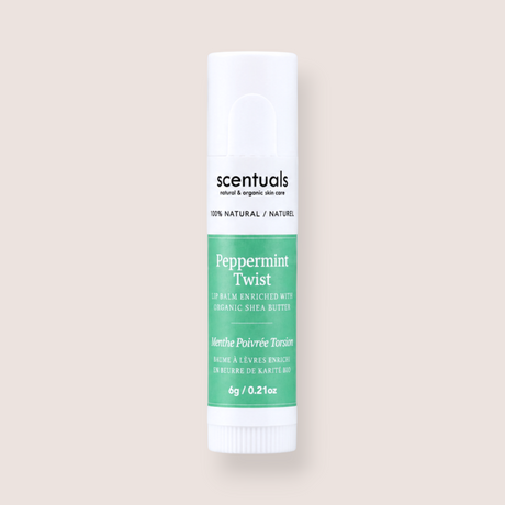 A tube of Scentuals Peppermint Twist lip balm, featuring a white container with a green label, centered on a solid pale beige background.