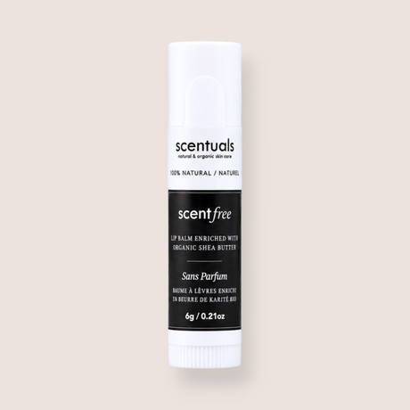 A single tube of Scentuals Scent Free lip balm with organic shea butter, shown against a solid, warm off-white background.