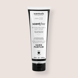 A squeeze tube of scentialss Scentfree Moisturizing Hand & Body Lotion on a solid light beige background. The tube is white with black text and black caps on the top and bottom.