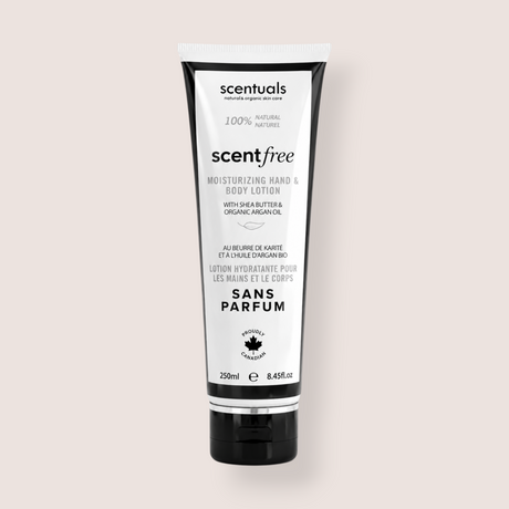 A squeeze tube of scentialss Scentfree Moisturizing Hand & Body Lotion on a solid light beige background. The tube is white with black text and black caps on the top and bottom.